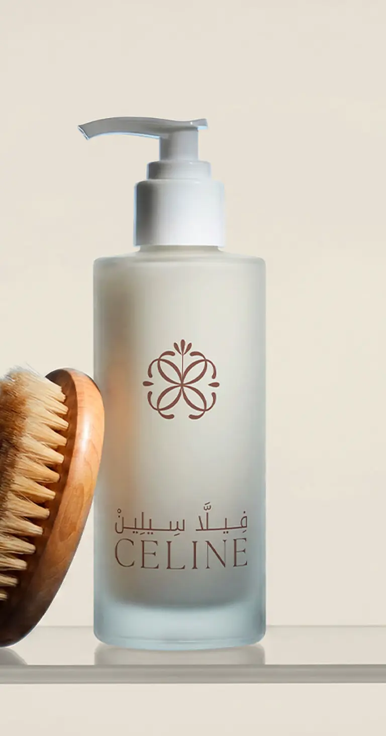 A frosted bottle bearing the Villa Celine logo, beside a wooden body brush.