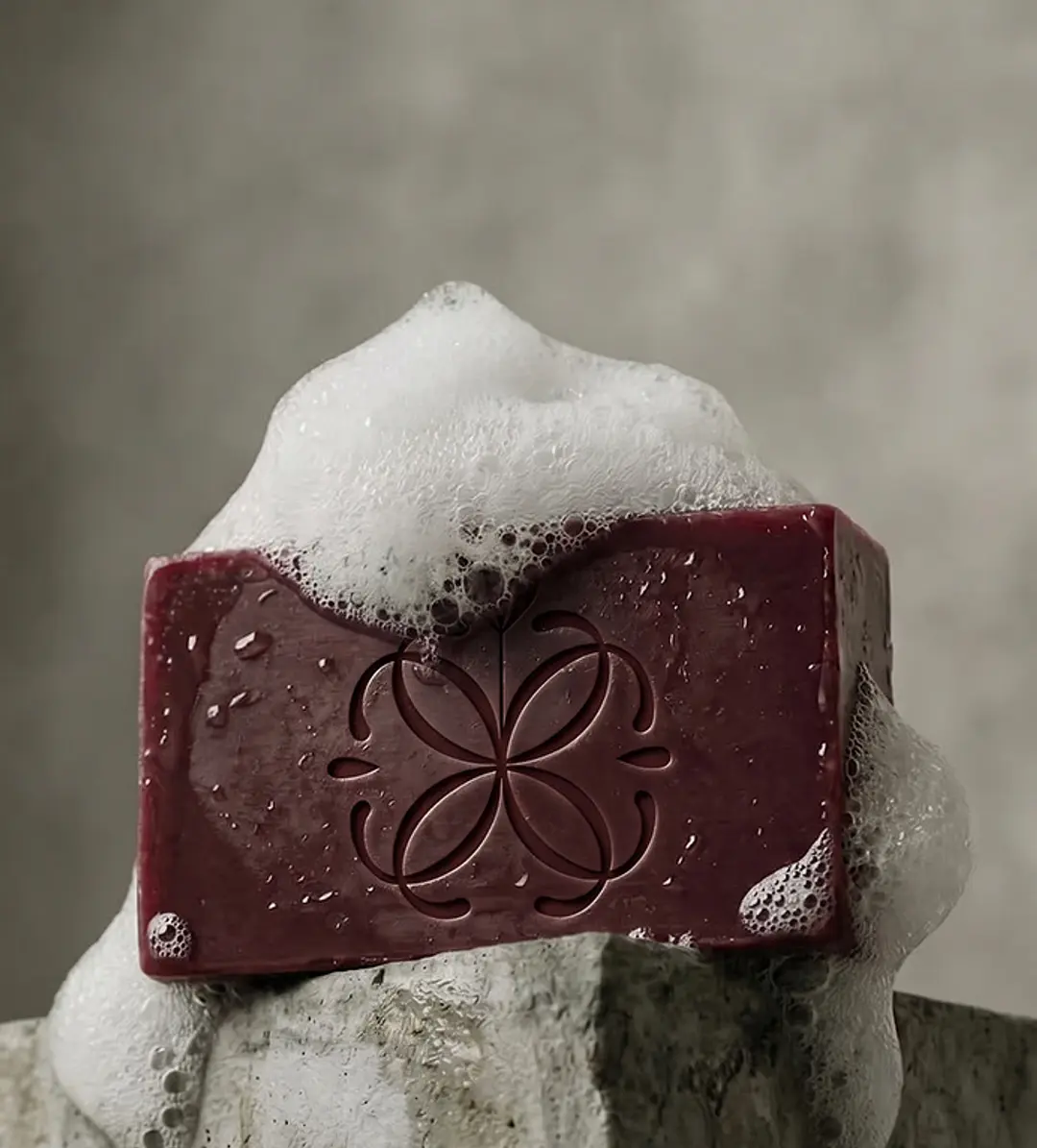 A deep-red soap bar bearing the Celine mark, crowned with soft foam.